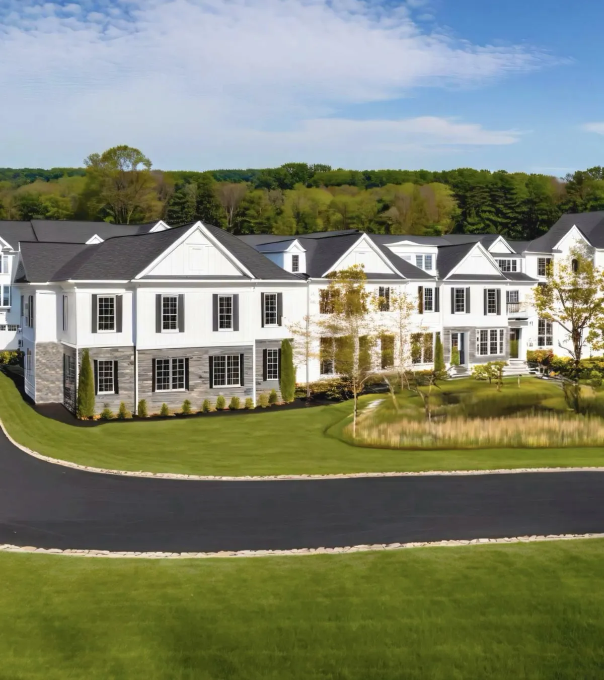 A row of newly built white New Jersey townhomes with manicured lawns at a premium residential development — the kind of community TRELIA's land-banking investments help create.